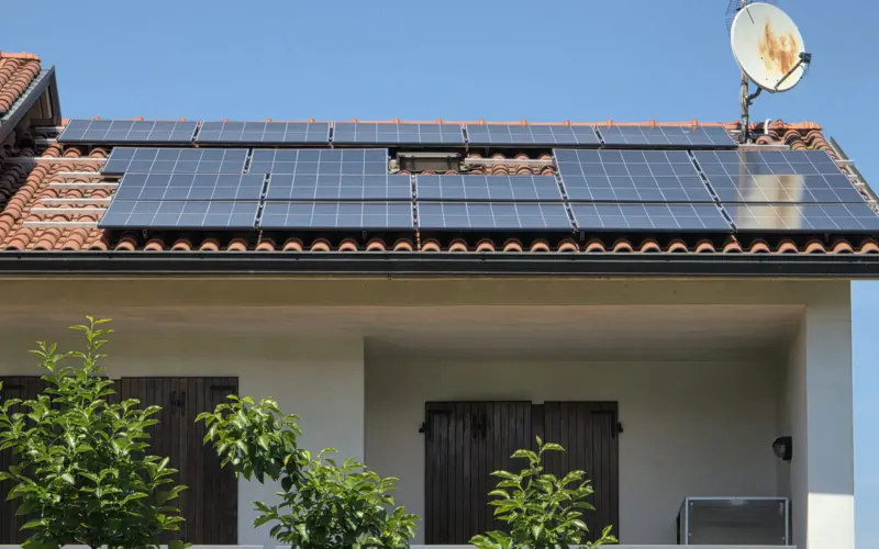 Tetto in coppi con due file di pannelli fotovoltaici neri sotto il cielo blu, impianto montato da Magikenergy